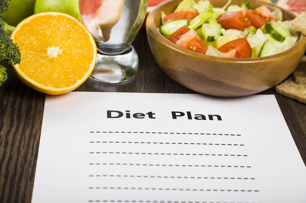 Food and sheet of paper with a diet plan on a dark wooden table. - Фото, зображення