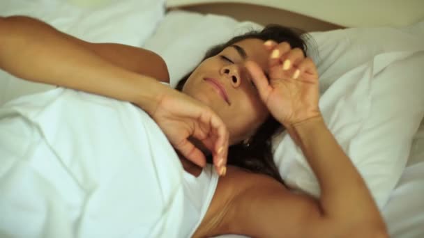 Young tanned brunette woman lying on the bed in the sunny morning. - Materiał filmowy, wideo