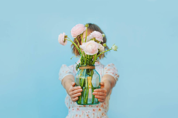 Girl with pink ranunculus bouquet at blue wall - Foto, Imagen