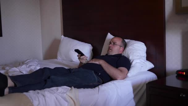 Man rests on a bed and watches TV - Video