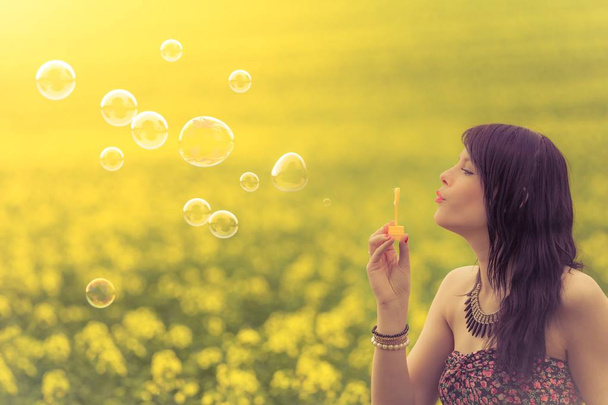 Beautiful woman blowing funny soap bubbles in summer nature - Photo, Image