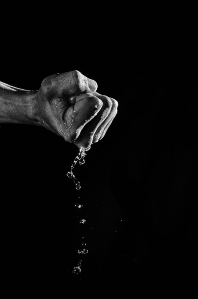 Puhdas vesi virtaa kädestä nyrkkiin puristettuna.
. - Valokuva, kuva
