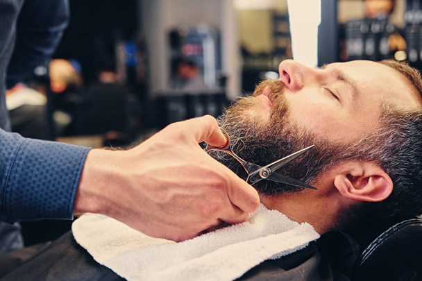 Barbiere taglia la barba dell'uomo
. - Foto, immagini
