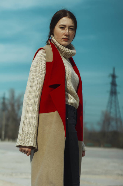 junges schönes Mädchen Modell in Weste Mantel von roter und beiger Farbe und im Rollkragen - Foto, Bild