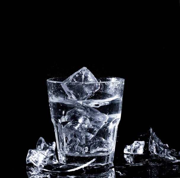 A glass with clear water and ice on a black background - Zdjęcie, obraz
