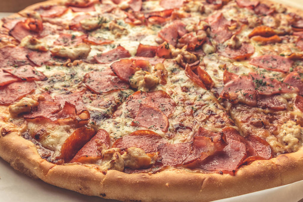 Pizza close-up foto, vleesingrediënten: ham, spek, kipfilet - Foto, afbeelding