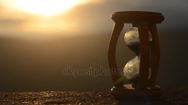 Tijd concept. Silhouet van zandloper klok en rook op de achtergrond wazig aard op zonsondergang tijd of symbolen van tijd onder de rook, tijd eindigt of liefde eindigt. Optimistisch of pessimistisch ideeën. - Video