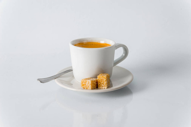 Café negro en taza blanca, cubitos de azúcar moreno en platillo
 - Foto, imagen