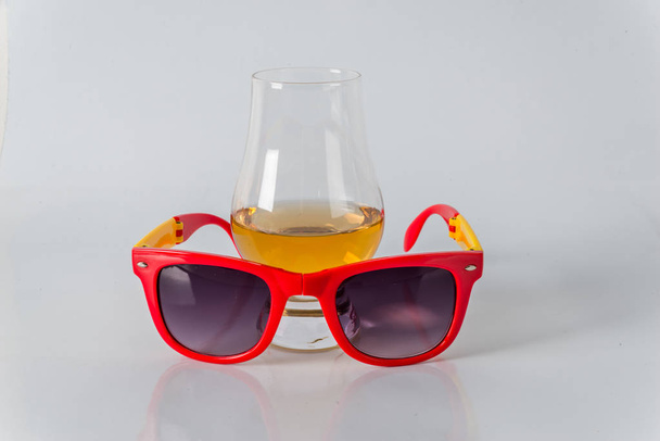 heerlijke single malt whisky glas met zonnebril op een witte b - Foto, afbeelding