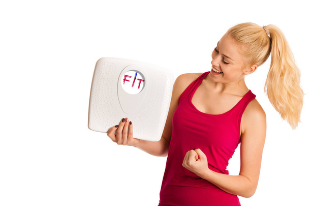 Happy young blond woman showing a scale as she has perfect shape - Φωτογραφία, εικόνα