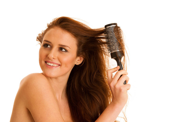Beautiful young woman combs her hair with a brush isolated over  - Фото, зображення