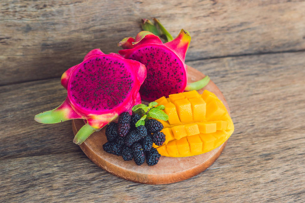 Sliced dragon fruit and mango on an old wooden background - Photo, Image