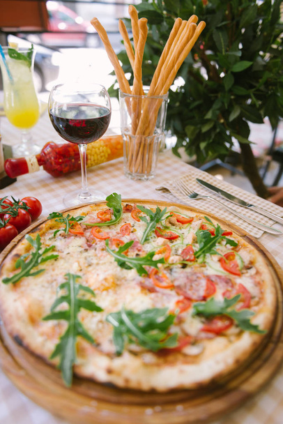 Pizza with glass of wine, on served table - Fotó, kép