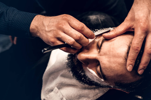 Friseur rasiert bärtigen Rüden mit scharfem Rasiermesser - Foto, Bild