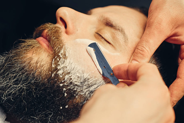 Borbély borotválkozás, szakállas férfi, egy éles borotva - Fotó, kép