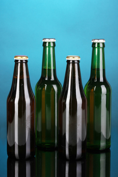 Coloured glass beer bottles on blue background - 写真・画像