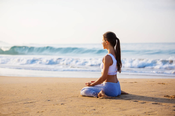 Caucasian woman practicing yoga at seashore of tropic ocean - Zdjęcie, obraz