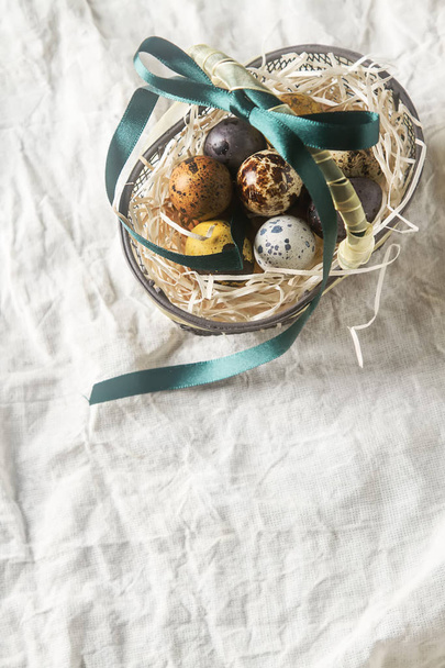 Multi-colored Easter egg. Quail eggs with feathers in basket. Da - Photo, image