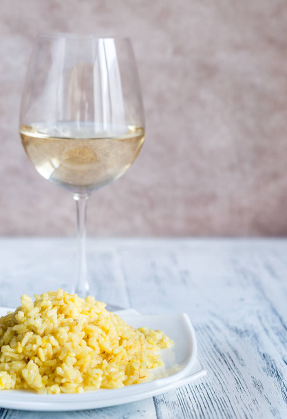Gedeelte van risotto met glas witte wijn - Foto, afbeelding