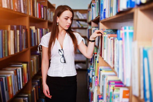 Brunette girl at library, wear on white blouse and black mini sk - Фото, изображение