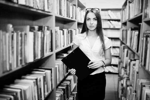 Brunette girl at library with folder of documents, wear on white - Фото, изображение