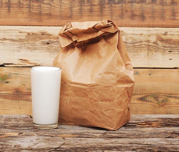 σακούλες μεσημεριανό χαρτί με γυαλί γάλα πέρα από το ξύλινο υπόβαθρο - Φωτογραφία, εικόνα