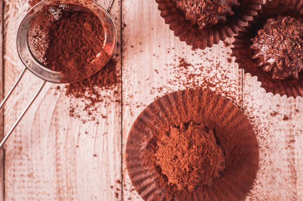 Muffin de viruta de chocolate en papel de cera marrón. Desenvuelto. Cacao en polvo en el fondo
 - Foto, imagen