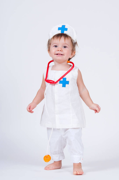 A cheerful laughing baby girl playing as a doctor with a stethoscope. - Foto, imagen