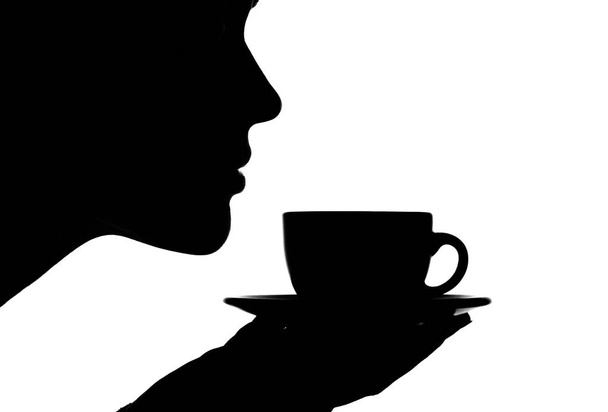 silhouette of a woman breathing the scent of tea in her cup o - Фото, изображение