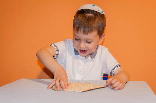 Αρκετά Καυκάσιος αγόρι παίζει με το παραδοσιακό matzah. - Φωτογραφία, εικόνα