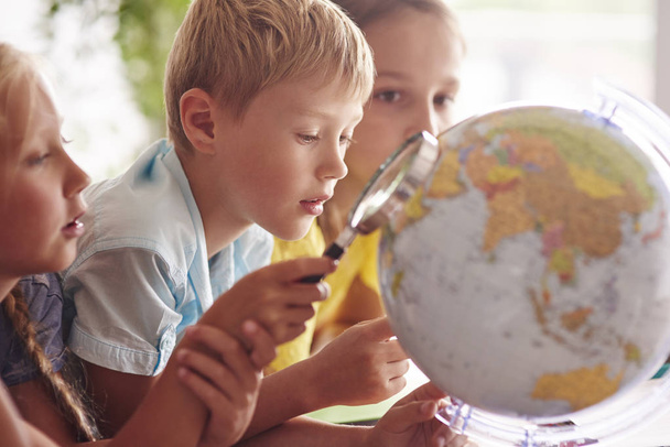 Children using magnifying glass and globe - Photo, Image