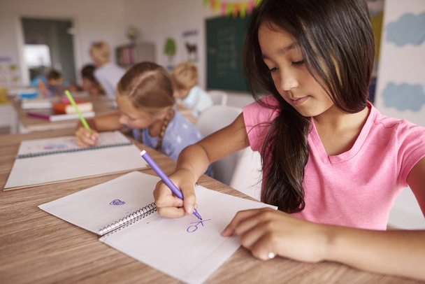 Schülerinnen zeichnen, während sie im Klassenzimmer sitzen - Foto, Bild