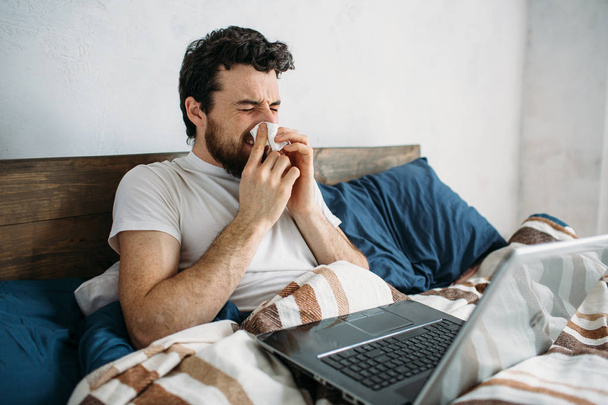 Bearded man lying in morning bed with laptop - Photo, image