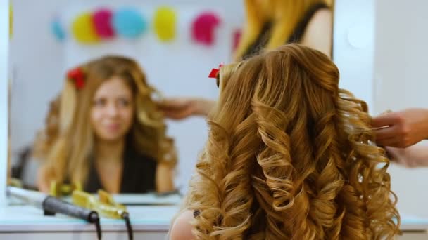 Divat stylist fodrász nem egy frizura, hogy az ügyfél egy szép, fiatal lány a divatos szalonban. Fodrászat frizura csinál szép lány, aki a tükörbe néz. - Felvétel, videó