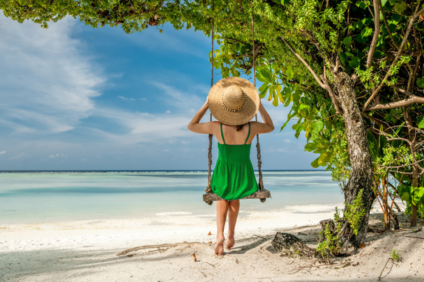 Mujer en vestido verde balanceándose en la playa
 - Foto, Imagen