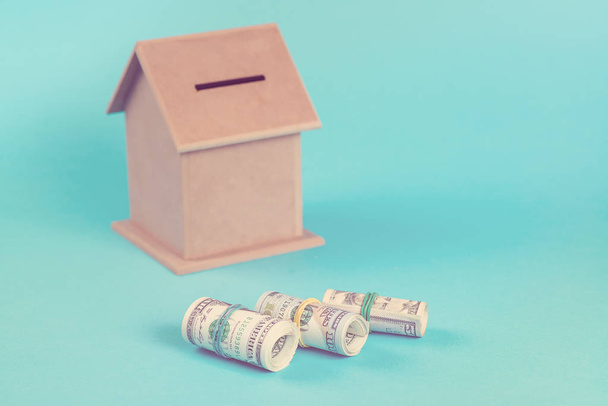 家を購入する金融貯蓄の概念。貯金箱、ロール、青の背景に分離されたドル。トーン. - 写真・画像