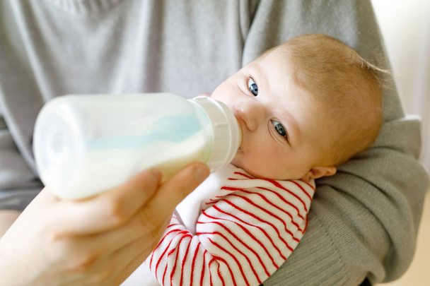 哺乳瓶にミルクで餌の生まれたばかりの赤ちゃん娘を父します。 - 写真・画像