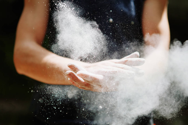Climber woman coating her hands in powder chalk magnesium. Ready for climbing - Foto, Bild