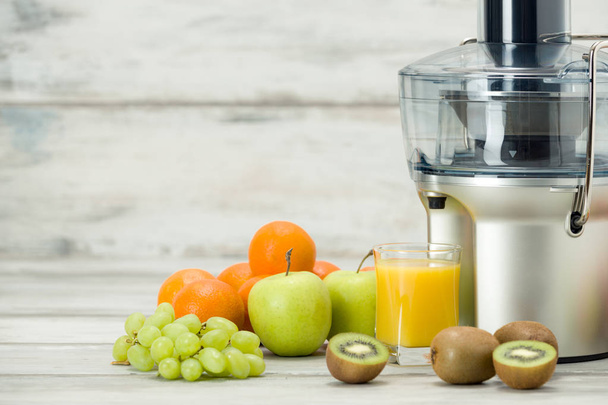Modern electric juicer, various fruit and glass of freshly made juice, healthy lifestyle concept - Foto, Imagem
