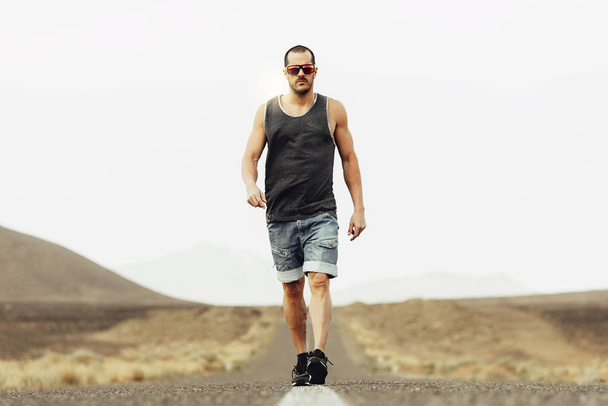 Handsome man walking along the desert. - Foto, afbeelding