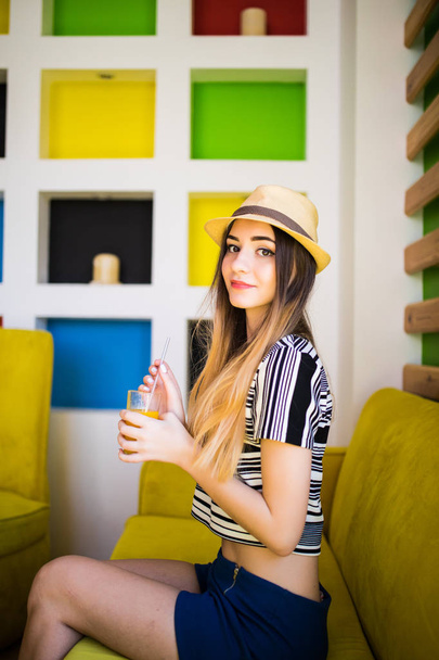 Pretty woman with fresh fruit juice cup wearing hat in cafe - Foto, immagini