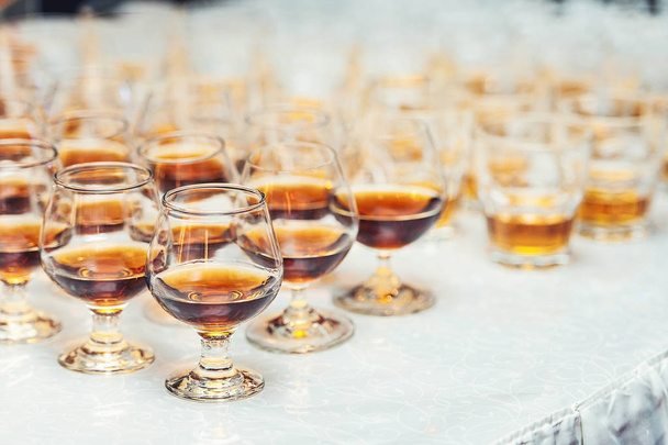 Reihe Gläser mit Whiskey oder Cognac auf dem Tisch. Starker Alkohol in einer Bar oder einem Restaurant. - Foto, Bild