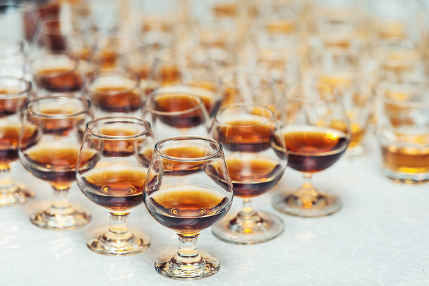 Reihe Gläser mit Whiskey oder Cognac auf dem Tisch. Starker Alkohol in einer Bar oder einem Restaurant. - Foto, Bild