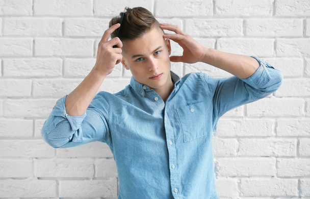 Handsome young man combing hair  - Photo, image