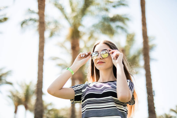 Frau mit Sonnenbrille auf Augen auf Sommerurlaub auf Palmen Hintergrund. Sommerberuf. - Foto, Bild