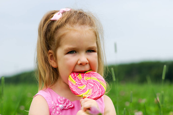  Το κοριτσάκι τρώει ένα γλειφιτζούρι. - Φωτογραφία, εικόνα