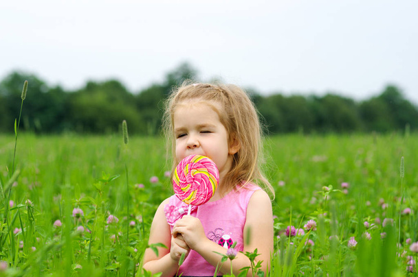  Mała dziewczynka jedząca lizaka - Zdjęcie, obraz