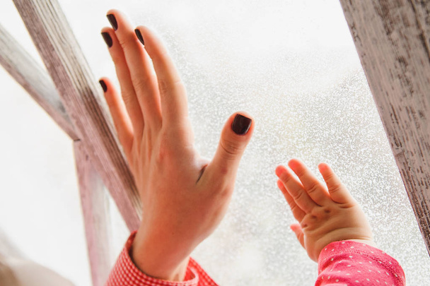 Hand of mother and child on a windowpane - Foto, Imagen