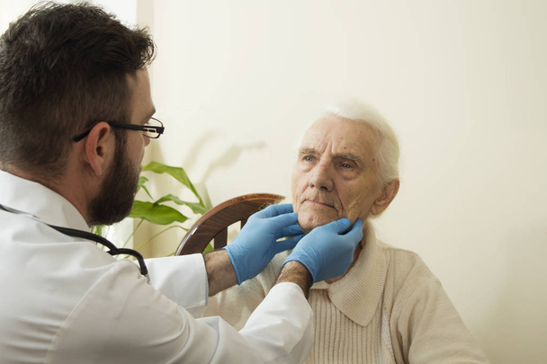 El médico examina los ganglios linfáticos del cuello de una anciana
.  - Foto, imagen