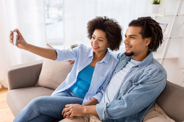 happy couple with smartphone taking selfie at home - Fotoğraf, Görsel